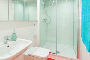 Helles Badezimmer mit Duschkabine, Wandwaschbecken und Wand-WC.
