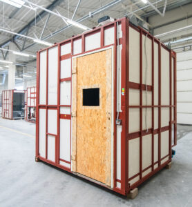 Vorgefertigtes Badmodul in der Fertigung, mit OSB-Tür und Fensterausschnitt.