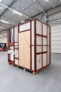 Vorgefertigtes Badmodul mit OSB-Tür auf Stahlrahmen, in der Produktionshalle.