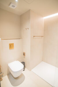 Minimalistisches beiges Badezimmer mit Wand-WC und Walk-in-Dusche.