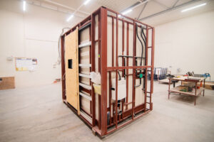 Vorgefertigtes Badmodul mit OSB-Tür und Sanitärinstallation am Rahmen.