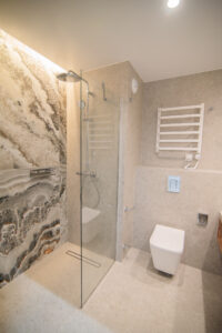 Badezimmer mit dekorativer Onyxwand, Walk-in-Dusche, Wand-WC und weißem Heizkörper.