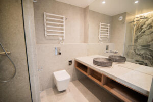 Badezimmer mit zwei Aufsatzwaschbecken auf Holzplatte, Walk-in-Dusche und dekorativer Steinwand.